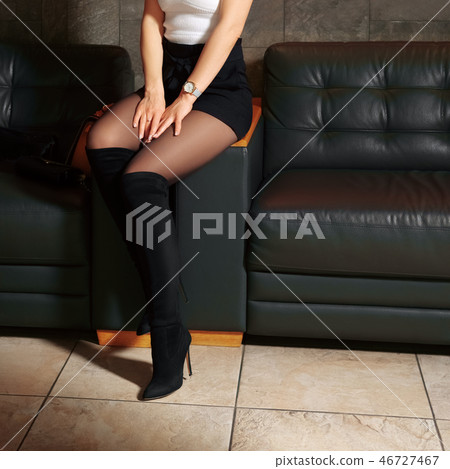 Female legs in pantyhose on leather sofa 46727467