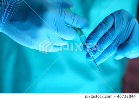 Physician injector arms in sterile uniform holding syringe 46732844