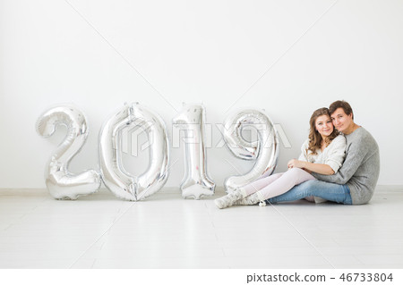 New 2019 Year is coming concept - Happy young man and woman with silver colored numbers on white 46733804