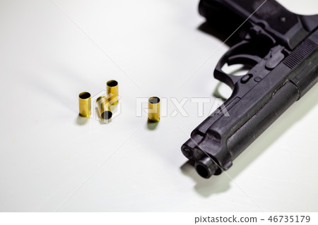 Handgun with 9mm shell casings on white table 46735179
