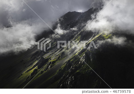 The epic view of the rocky slope in the sunset and low clouds. Elbrus North Caucasus. Rocky wall The epic view of the rocky slope in the sunset and low clouds. Elbrus North Caucasus. Rocky wall 46739578