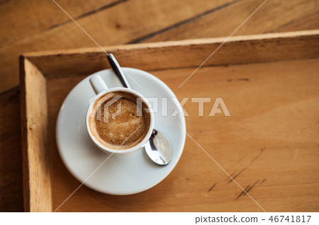 top view of white Cup with black coffee on a white saucer and teaspoon on wooden background top view of white Cup with black coffee on a white saucer and teaspoon on wooden background 46741817