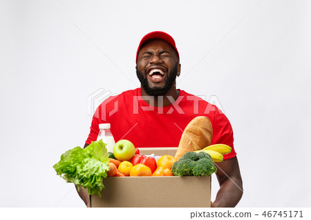 Delivery Concept - Handsome African American delivery man carrying package box of grocery food and 46745171