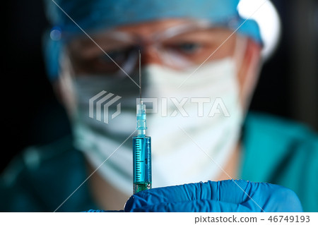 Physician injector arms in sterile uniform holding syringe 46749193