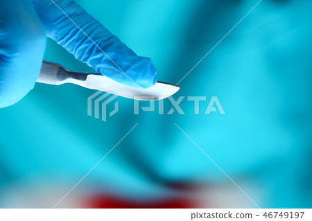 Surgeon arms in sterile uniform holding sharp knife Surgeon arms in sterile uniform holding sharp knife 46749197
