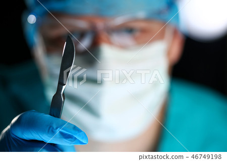 Surgeon arms in sterile uniform holding sharp knife 46749198