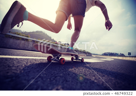 Skateboarder skateboarding on highway road Skateboarder skateboarding on highway road 46749322