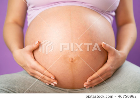 Pregnant woman holding her hands on tummy belly. Young girl expecting baby on pink bakcground Pregnant woman holding her hands on tummy belly. Young girl expecting baby on pink bakcground 46750962