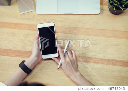 woman holding a blank screen phone and a laptop. 46752043