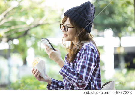 女人看著智能手機在公園裡 女人看著智能手機在公園裡 46757828