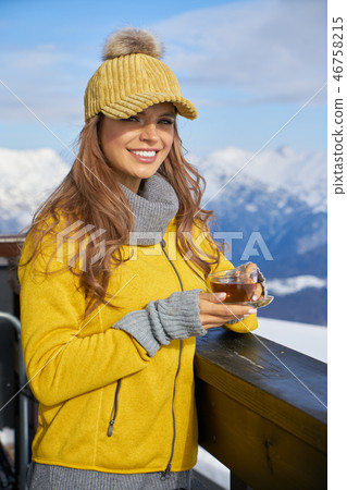 Woman drinking warm tea in the rustick wooden terrace on mountai Woman drinking warm tea in the rustick wooden terrace on mountai 46758215