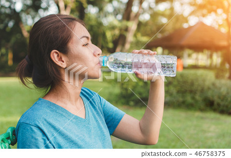 woman runner relaxing drinking water in bottle. woman runner relaxing drinking water in bottle. 46758375