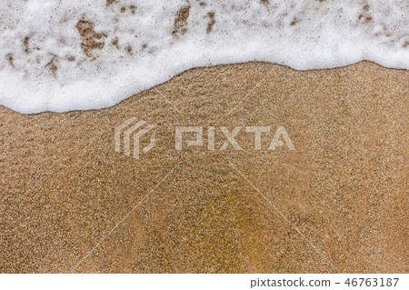 Top view of surface of clean golden sand at sea beach and white foamy wave Top view of surface of clean golden sand at sea beach and white foamy wave 46763187
