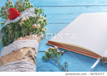 Bouquet of flowers and an empty notebook on table 46763577