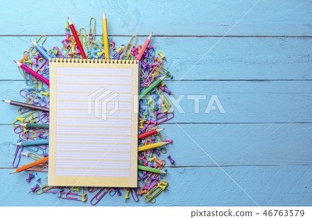 Colored crayons, paper clips, pins, and a notebook 46763579