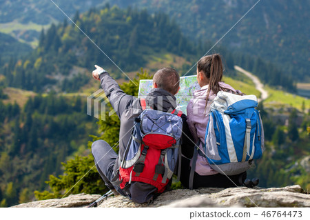 Smiling adventure couple with map on slope. look at map Smiling adventure couple with map on slope. look at map 46764473