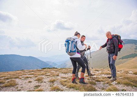 An elderly man giving a tour for a young group of people 46764833