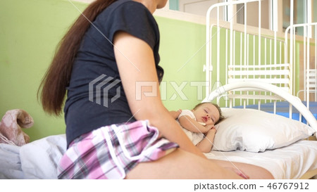 child sleeps in the hospital ward on white bed under the supervision of mom. mother measures 46767912