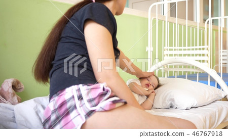child sleeps in the hospital ward on white bed under the supervision of mom. mother measures child sleeps in the hospital ward on white bed under the supervision of mom. mother measures 46767918