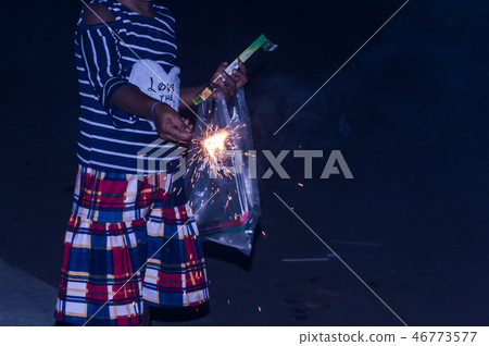 Kid holding sparklers on black background Kid holding sparklers on black background 46773577