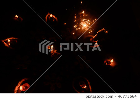 A burning Sparklers on hand over Diya-oil Lamps A burning Sparklers on hand over Diya-oil Lamps 46773664