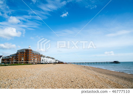 A pier in the suburbs of England connected by a red brick mansion and a pier standing just on a gravel beach by the sea A pier in the suburbs of England connected by a red brick mansion and a pier standing just on a gravel beach by the sea 46777510