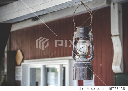 Old oil lamp hanging on a porch outside 46778438