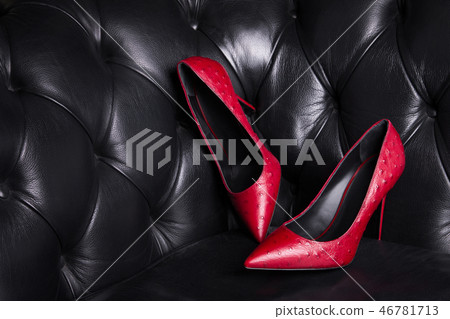 Two red leather shoes on a dark background.  46781713