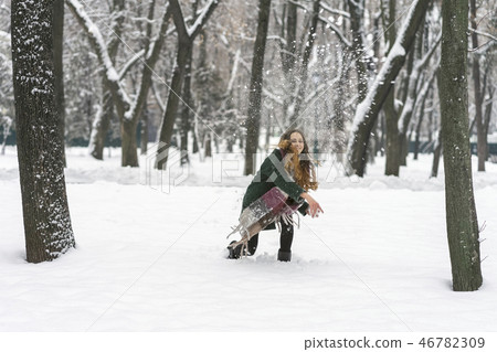 woman in the park throwing snowballs 46782309
