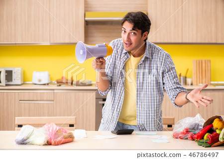 Young man calculating expences for vegetables in kitchen Young man calculating expences for vegetables in kitchen 46786497