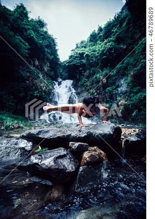 Young woman practice yoga near waterfall in forest Young woman practice yoga near waterfall in forest 46789689