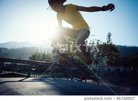 Skateboarder doing ollie at skatepark ramp Skateboarder doing ollie at skatepark ramp 46789807