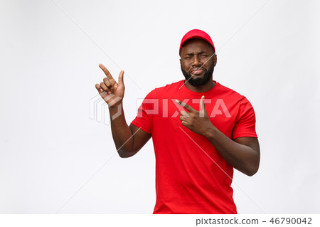 Portrait of handsome african american delivery man annoying pointing finger on side. Isolated over Portrait of handsome african american delivery man annoying pointing finger on side. Isolated over 46790042