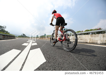 Woman cyclist riding Mountain Bike on highway Woman cyclist riding Mountain Bike on highway 46791453