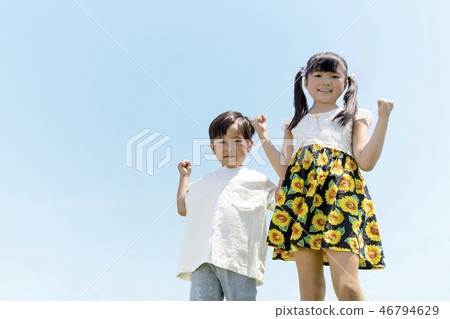 Two sisters who make a guts pose against the blue sky back Two sisters who make a guts pose against the blue sky back 46794629