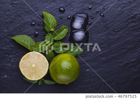 Fresh ripe limes with mint on black slate stone background. 46797525