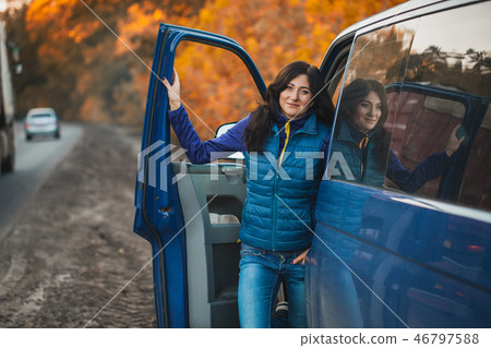 brunette woman driver near the car in the autumn forest brunette woman driver near the car in the autumn forest 46797588