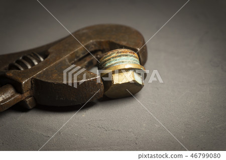 Adjustable wrench on a dark cement background Adjustable wrench on a dark cement background 46799080