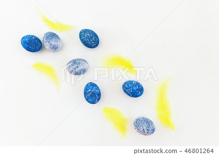 Easter eggs and bright yellow feather on white Easter eggs and bright yellow feather on white 46801264