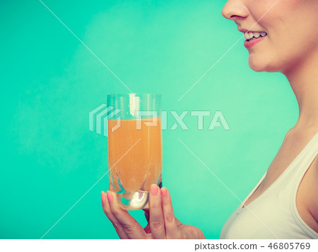 Woman holding glass of orange flavored drink 46805769
