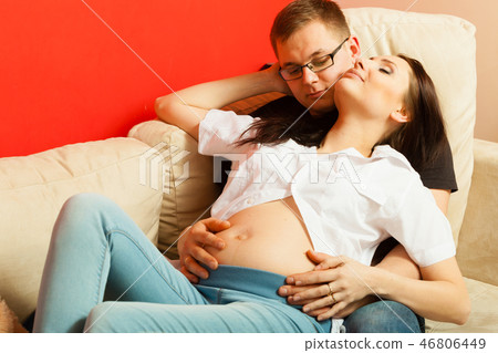 Pregnant woman and man relaxing on sofa Pregnant woman and man relaxing on sofa 46806449