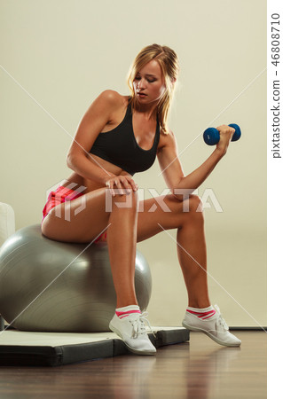 Woman with gym ball and dumbbell doing exercise Woman with gym ball and dumbbell doing exercise 46808710
