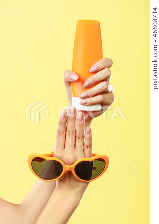 Woman holds sunglasses sunscreen lotion Woman holds sunglasses sunscreen lotion 46808714