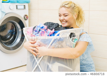 Woman holding laundry basket full of clothes Woman holding laundry basket full of clothes 46808718