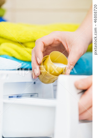 Hand pouring fabric softener into washing machine Hand pouring fabric softener into washing machine 46808720