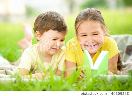 Little girl and boy are reading book outdoors Little girl and boy are reading book outdoors 46809228