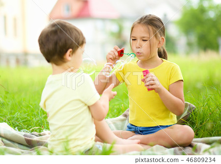 Little girl and boy are blowing soap bubbles Little girl and boy are blowing soap bubbles 46809234