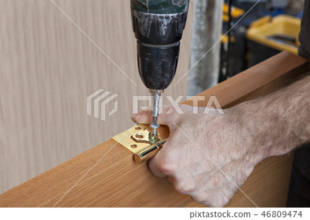 carpenter is tightening screws using screwdriver carpenter is tightening screws using screwdriver 46809474