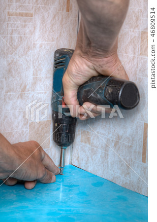 Laborer twists mounting screw into plastic panel Laborer twists mounting screw into plastic panel 46809514