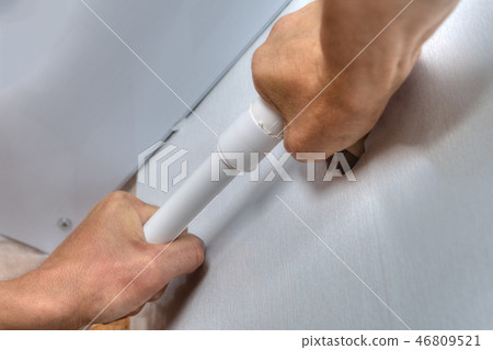Hands install plastic plumbing pipe on wall 46809521